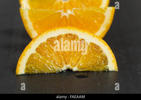 Gros plan d'une tranche d'orange fruit juteux sur ardoise naturelle de la pierre. Selective focus sur la partie avant de fruits. Banque D'Images