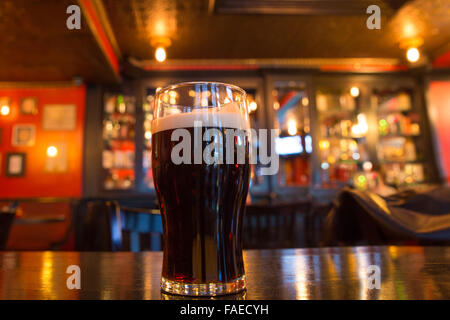 Verre de bière brune dans l'établissement pub Banque D'Images