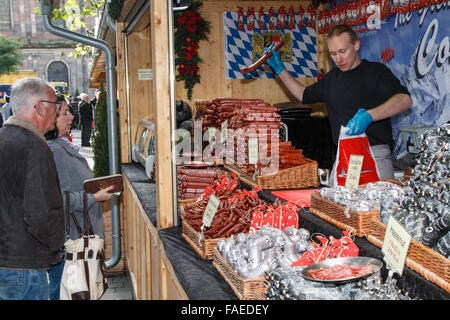 Saucisse allemande d'être vendu à un client à partir d'un stand au marché marché de Noël de Manchester. Banque D'Images