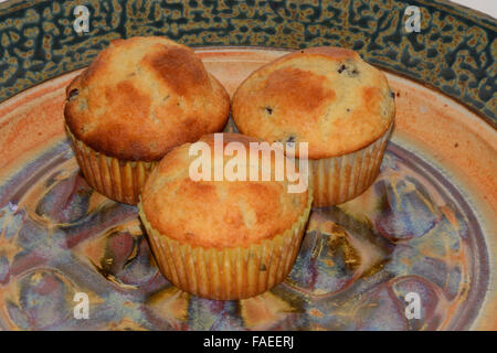 Muffins aux bleuets dans trois moules à muffin en papier sur la plaque de céramique multicolores Banque D'Images