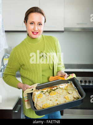 Happy housewife la cuisson du poisson en filets à cuisine Banque D'Images