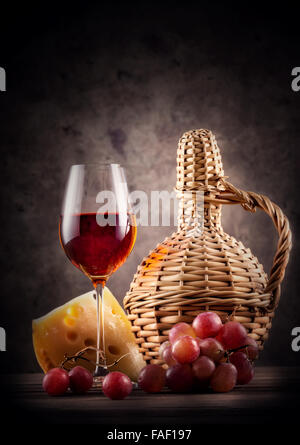 Verre de vin rouge avec carafe et raisins sur fond sombre Banque D'Images