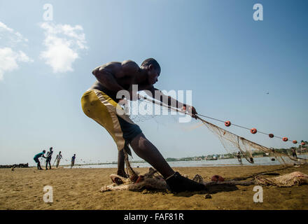 Un pêcheur tire dans ses prises sur une plage à Freetown, Sierra Leone. Banque D'Images