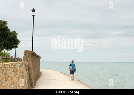 Une femme marche sur la côte près de la mer sur l'île de Wight Royaume-uni le jour d'un ciel couvert Banque D'Images