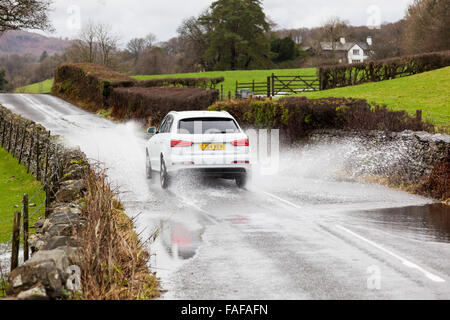 Une voiture conduit par l'eau de surface sur la B5285 près de Hawkshead, Lake District, Cumbria Banque D'Images