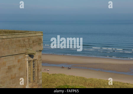 L'équitation le long de plage de Bamburgh vu du château de Bamburgh. Le Northumberland. L'Angleterre. UK. L'Europe Banque D'Images