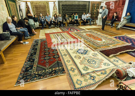 Turquie voyage - vente de tapis et de l'artisanat près de Pergame. Montrant au large de produits à un groupe de touristes. Banque D'Images