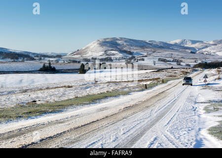 Voiture sur A683 près de Kirkby Stephen qui est recouverte de neige, avec en arrière-plan Cap Sud Fells, Cumbria, Royaume-Uni. Banque D'Images