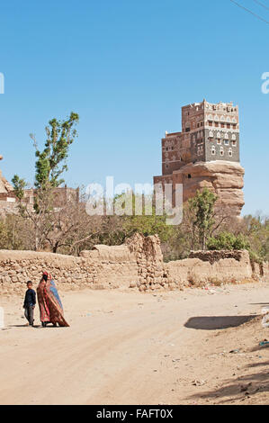 Une femme voilée et un enfant marcher près de Dar al-Hajar, Dar al Hajar, le Rock Palace, palais royal, symbole iconique du Yémen Banque D'Images