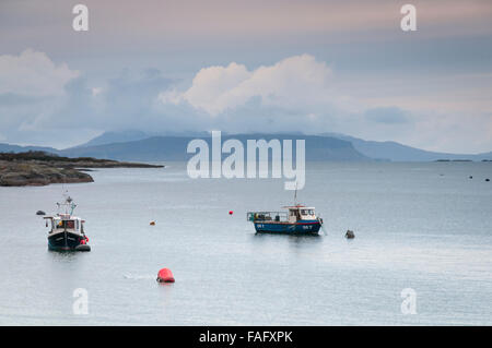 Deux petits bateaux de pêche au mouillage dans la baie de Glenuig avec les petites îles de rhum et d'Eigg en arrière-plan, Moidart, Ecosse Banque D'Images