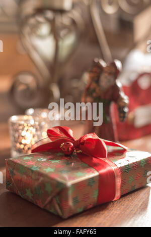 Wrapped Christmas présent sur une table, avec d'autres objets de Noël. Banque D'Images