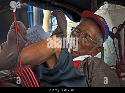 Un Becak conducteur prend une sieste dans la chaleur de l'après-midi Banque D'Images