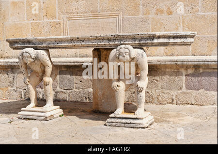 Une table en pierre médiévale est soutenue par deux statues de l'homme courbé, Notre Dame sur l'île de roches, le Monténégro. Banque D'Images