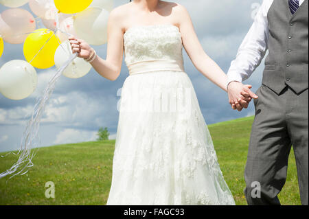 Une jeune mariée et ont toiletté tenant la main le jour de leur mariage Banque D'Images
