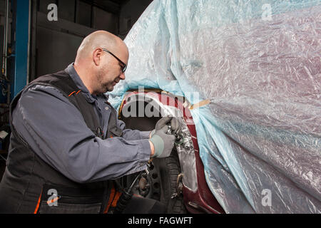 Location-corps cabinet travaille sur une aile avec une meuleuse d'angle. Banque D'Images