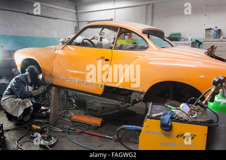 Carrossier restaure un classic car VW Karmann Ghia. Travaux de soudure à la carrosserie du véhicule. Banque D'Images