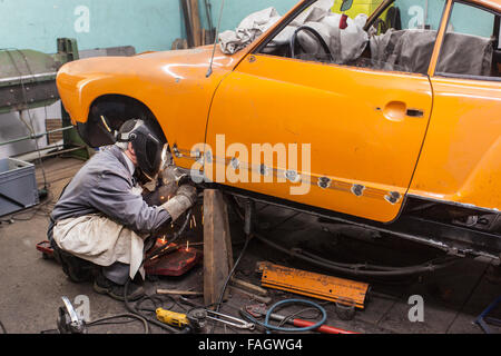 Carrossier restaure un classic car VW Karmann Ghia. Travaux de soudure à la carrosserie du véhicule. Banque D'Images