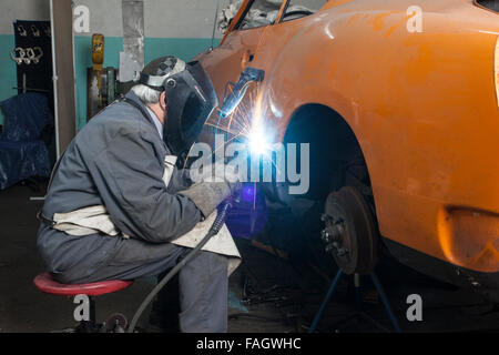 Carrossier restaure un classic car VW Karmann Ghia. Travaux de soudure à la carrosserie du véhicule. Banque D'Images