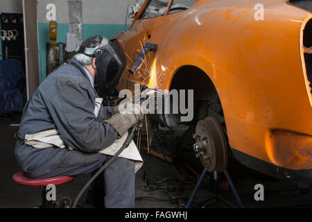 Carrossier restaure un classic car VW Karmann Ghia. Travaux de soudure à la carrosserie du véhicule. Banque D'Images