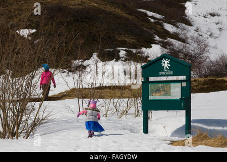 Une famille et petit enfant habillé dans des vêtements colorés à pied dans un parc public de la périphérie d'Isafjordur, Islande Westfjords, Banque D'Images