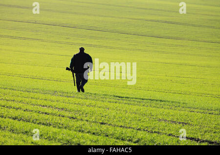 Un homme prenant position au cours d'un tournage d'hiver sur les terres agricoles dans la région de North Norfolk. Banque D'Images