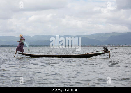 Un pêcheur de l'ethnie Intha people rowing son bateau sur le lac Inle au Myanmar (Birmanie). L'homme est l'un des rameurs de la jambe, qui peut row Banque D'Images