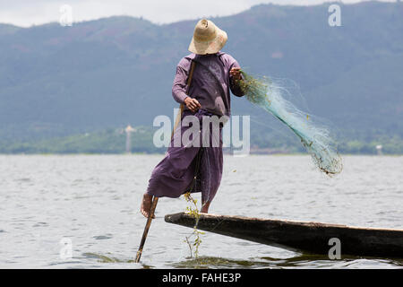 Un pêcheur de l'ethnie Intha people rowing son bateau sur le lac Inle au Myanmar (Birmanie). L'homme est l'un des rameurs de la jambe, qui peut row Banque D'Images