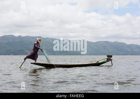 Un pêcheur de l'ethnie Intha people rowing son bateau sur le lac Inle au Myanmar (Birmanie). L'homme est l'un des rameurs de la jambe, qui peut row Banque D'Images