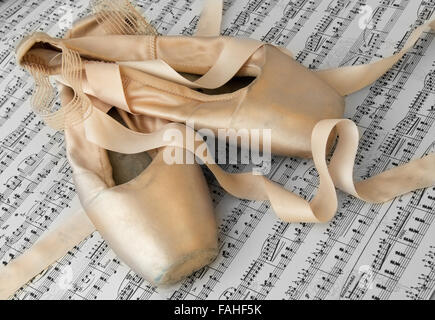 Ancienne paire de chaussons de ballet utilisé sur une feuille de musique Banque D'Images