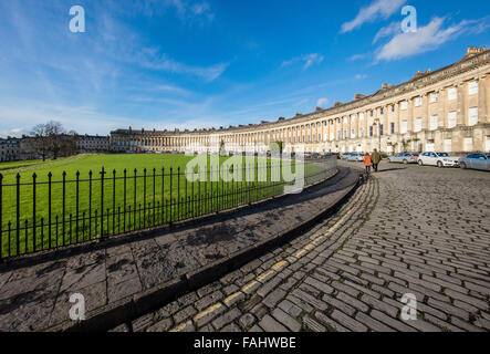 Un couple marche le long de la route pavée en face de l'Royal Crescent à Bath UK Banque D'Images