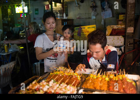 Vendeurs de Rue de la famille à Khao San Road, Bangkok, Thaïlande. Khaosan Road ou Khao San Road est une petite rue dans le centre de Bangkok, Thaïlande. C'est dans la région de Banglamphu (Phra Nakhon district) sur 1 km (0,62 mi) au nord du Grand Palais et Wat Phra Kaew. 'Khaosan' signifie 'milled rice', un rappel que dans l'ancien temps de la rue était un important marché du riz Bangkok. Au cours des 20 dernières années, toutefois, Khaosan Road est devenue une célèbre 'backpacker ghetto". Il propose un hébergement bon marché, allant de «matelas dans une boîte de style des hôtels à prix raisonnable 3 étoiles hôtels. Banque D'Images