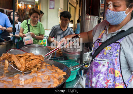 Je Noi, bananes frites, décrochage kluay keak dans Thanon Charoen Krung, Bangkok, Thaïlande. Fried banana panier, coin de Charoen Krung et Si Wiang. Ouvert tous les jours en milieu de matinée à la fin de l'après-midi. Vous pouvez voir comment les bananes, les patates douces, le taro et racines sont fiévreusement pelés, tranchés, et frits à répondre à la demande. Vous ne pouvez pas manquer ce panier alimentaire situé à droite au coin de Charoen Krung et Si Wiang. Les intervenants à l'heure actuelle, le premier lot de pâte-bananes frites hits l'huile jusqu'à ce que tout fonctionne. Banque D'Images