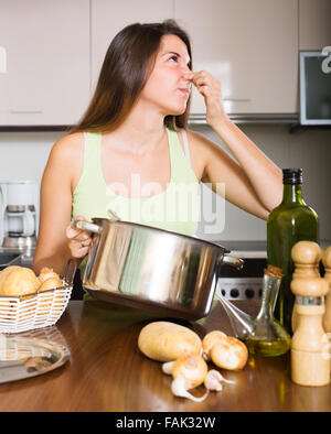 Jeune fille prend couvercle de casserole et sentir le renfermé à la maison cuisine Banque D'Images