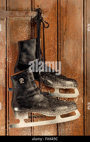 Vieux patins à glace accroché sur une porte en bois avec des flocons Banque D'Images