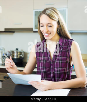 Femme heureuse avec des papiers à la maison cuisine Banque D'Images