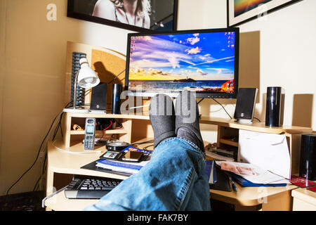 Pieds sur 24 office worker se détendre devant l'écran de l'ordinateur les jambes croisées UK Angleterre Banque D'Images