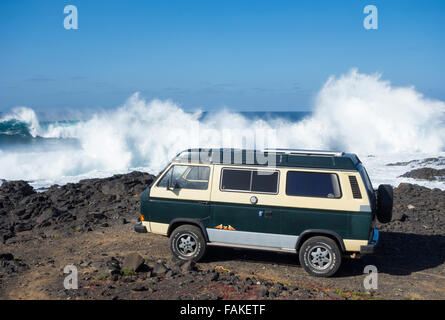 4x4 VW camper van avec panneau solaire sur toit garé sur un plage de surf avec d'énormes vagues se brisant. Gran Canaria, Îles Canaries. Banque D'Images