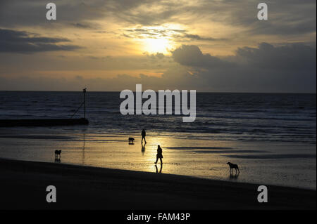 Les gens à pied leurs chiens sur la plage au lever du soleil le jour du Nouvel An à Littlehampton, West Sussex, Angleterre. Banque D'Images