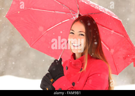 Beauté femme en rouge avec un parapluie dans un hiver enneigé Banque D'Images