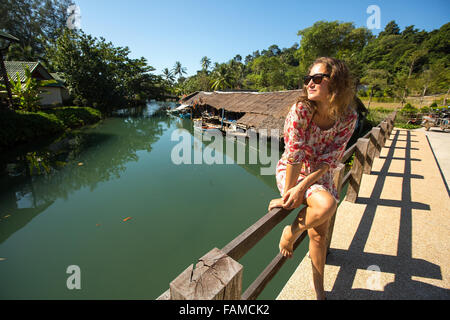 Beau portrait femme assise sur le pont sur la rivière dans le village de pêcheurs d'Asie. Banque D'Images