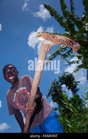 Jeune garçon travaillant dans le secteur avec une houe traditionnelle. Au Kenya. Banque D'Images