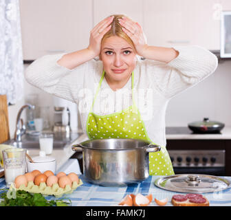 Jeune femme blonde prend couvercle de casserole et sentir le renfermé à la maison cuisine Banque D'Images