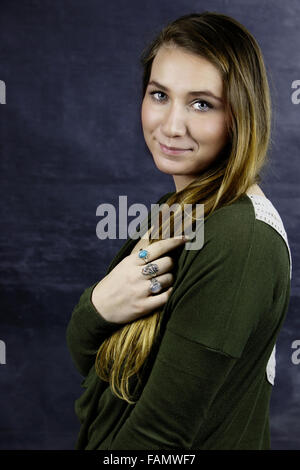 Studio portrait of teenage girl holding de longs cheveux blonds smiling Banque D'Images