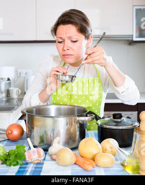 Jeune femme prend couvercle de casserole et sentir le renfermé à la maison cuisine Banque D'Images