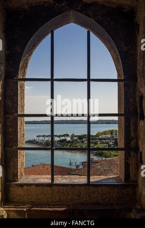 Vue sur le lac de Garde (Italie) et Sirmione vieille ville à travers la fenêtre de l'ancien Château Scaliger (Sirmione, Italie). Banque D'Images