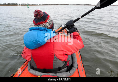 Jeune femme en éléments avancés d'hiver sur la pagaie kayak Convertible large Hickling, Norfolk Broads, Parc National Banque D'Images