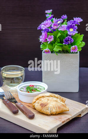 Feuilletés au curry avec sauce douce sur plaque de bois Banque D'Images