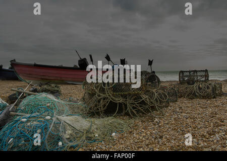 Ciel menaçant et sombre sur la plage à Bognor Regis. Les filets de pêche des casiers à homard et un bateau de pêche sur la plage de galets. Banque D'Images