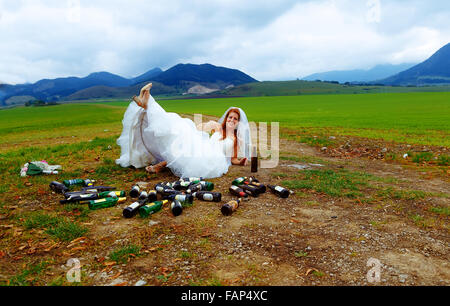 Drunken mariée avec beaucoup de bouteilles de bière vides dans paysage de montagnes - concept de mariage drôle Banque D'Images