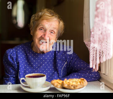 Grand-mère russe de boire du thé avec des gâteaux. Banque D'Images